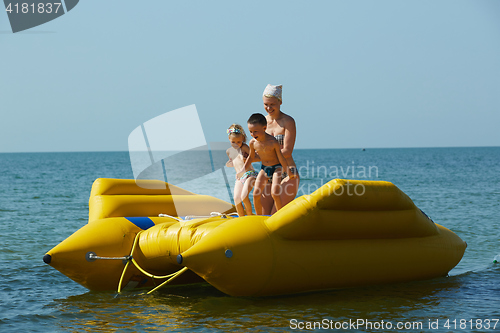 Image of two children with mom on the dinghy sailing at sea in summer