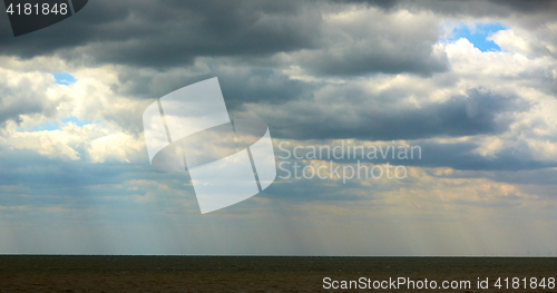 Image of Sun beam through heavy sky over calm sea