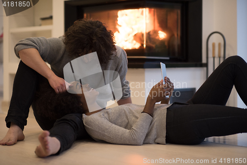 Image of multiethnic couple used tablet computer on the floor