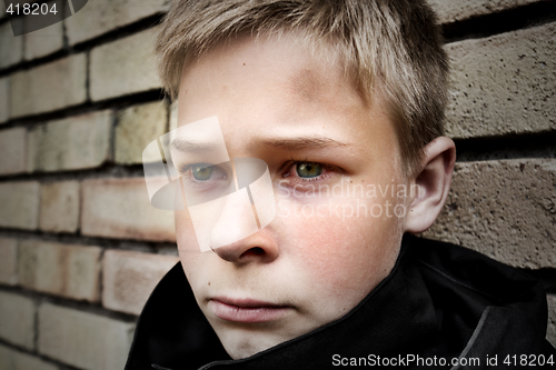 Image of upset boy leaning against a wall