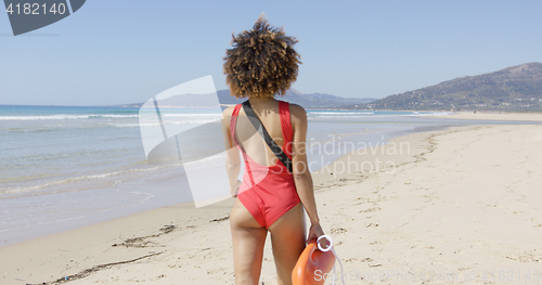 Image of Female lifeguard goes along beach