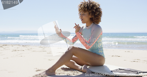 Image of Smiling female on beach using smartphone 