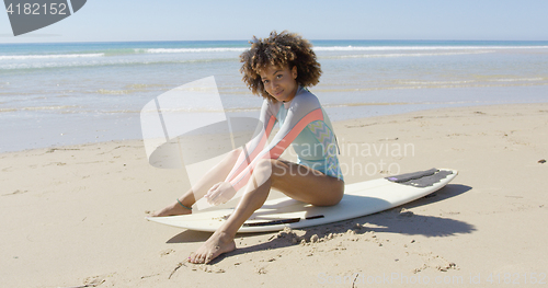 Image of African woman sitting on surfboard