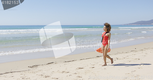 Image of Lifeguard with rescue float walking along beach