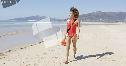 Image of Female lifeguard walking along beach