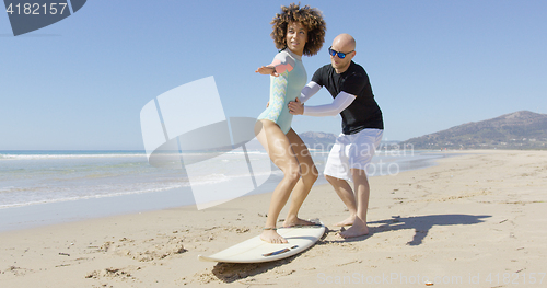 Image of Man teaching woman standing on surf