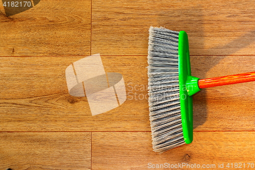 Image of cleaning wooden floor with broom