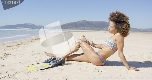 Image of Female sitting on beach with flippers