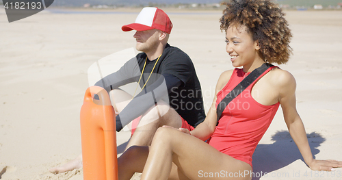 Image of Smiling lifeguards sitting on beach