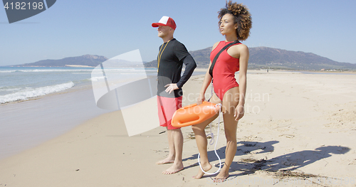 Image of Female and male lifeguards posing on beach