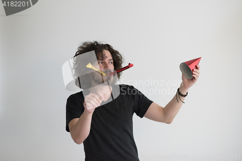 Image of Portrait of a man in party hat blowing in whistle