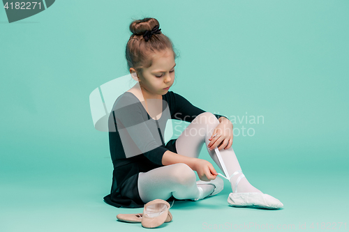 Image of Beautiful little ballerina in black dress for dancing puting on foot pointe shoes