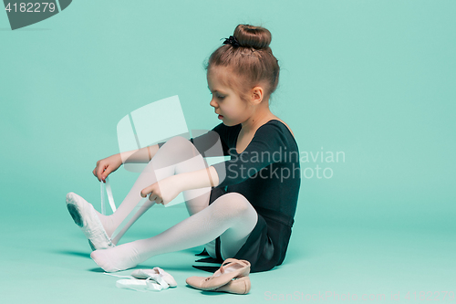 Image of Beautiful little ballerina in black dress for dancing puting on foot pointe shoes