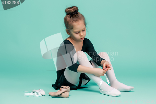 Image of Beautiful little ballerina in black dress for dancing puting on foot pointe shoes