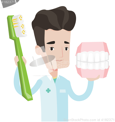 Image of Dentist with dental jaw model and toothbrush.