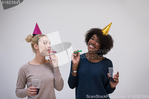 Image of smiling women in party caps blowing to whistles