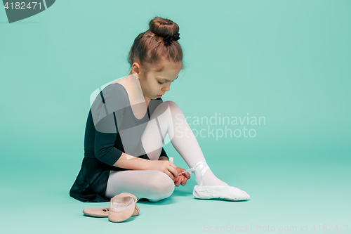 Image of Beautiful little ballerina in black dress for dancing puting on foot pointe shoes