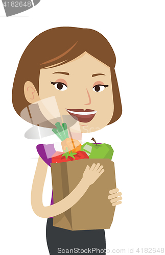 Image of Happy woman holding grocery shopping bag.
