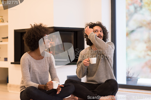 Image of multiethnic couple  in front of fireplace