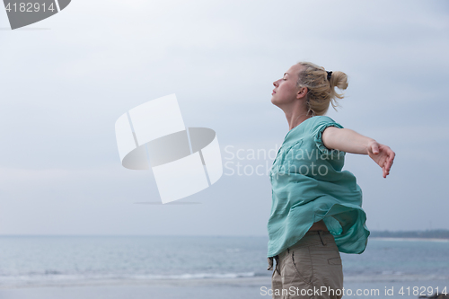 Image of Free woman enjoying windy weather on beach on overcast day