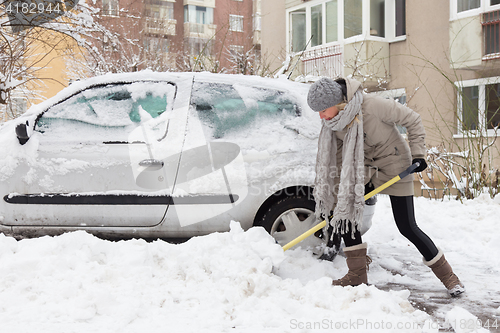 Image of Independent woman shoveling snow in winter.