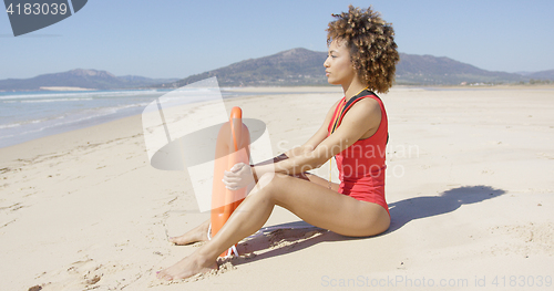 Image of Lifeguard sitting with rescue float on beach