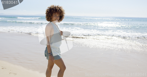 Image of Female wearing jumpsuit walking along beach