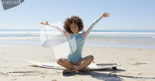 Image of Woman on surfboard with hands up