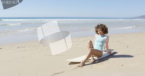 Image of Young woman sitting on a surfboard