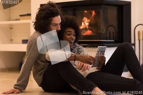 Image of multiethnic couple used tablet computer on the floor