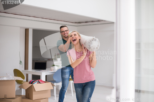 Image of couple carrying a carpet moving in to new home