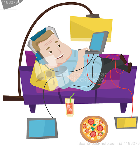 Image of Man lying on sofa with many gadgets.