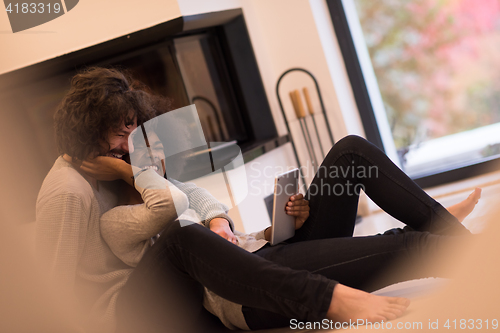 Image of multiethnic couple used tablet computer on the floor