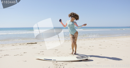 Image of Female listening music and dancing on beach