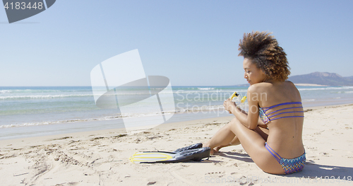 Image of Female with flippers sitting on beach