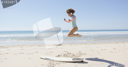 Image of Female listening music and jumping on beach