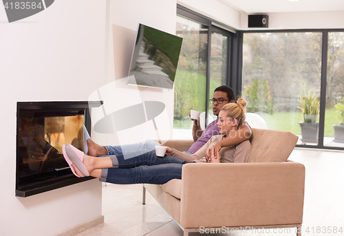 Image of Young multiethnic couple  in front of fireplace