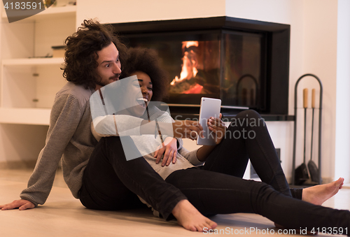 Image of multiethnic couple used tablet computer on the floor