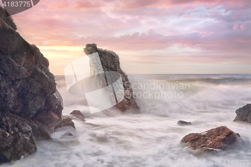 Image of Wave surges through rocky coastline at sunrise