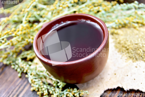 Image of Tea with wormwood in clay cup on dark board