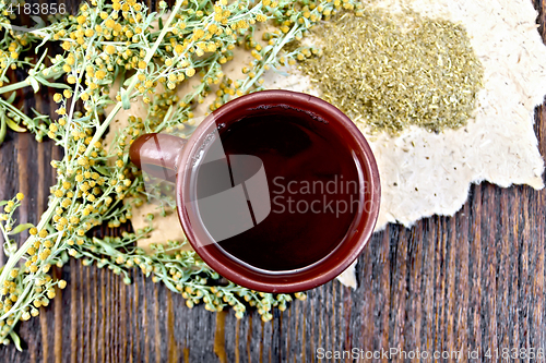 Image of Tea with wormwood in clay cup on board top