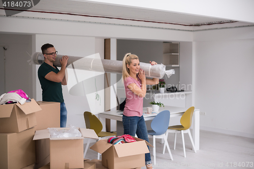 Image of couple carrying a carpet moving in to new home