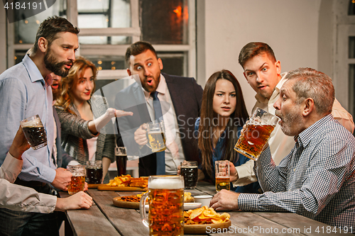 Image of Group of friends enjoying evening drinks with beer