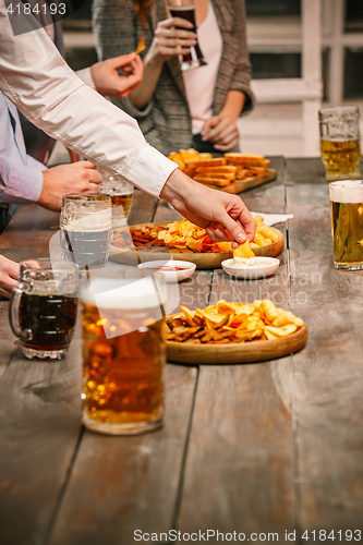 Image of Group of friends enjoying evening drinks with beer