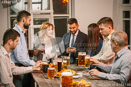 Image of Group of friends enjoying evening drinks with beer