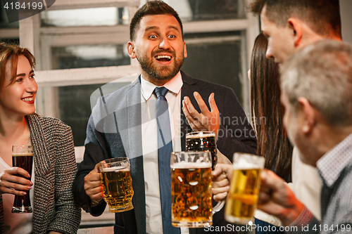 Image of Group of friends enjoying evening drinks with beer