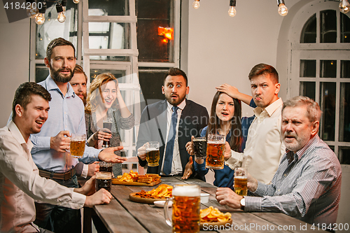 Image of Group of friends enjoying evening drinks with beer