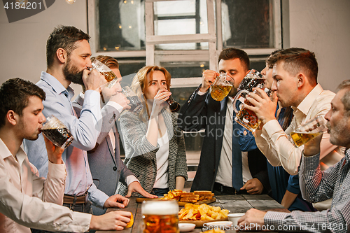 Image of Group of friends enjoying evening drinks with beer