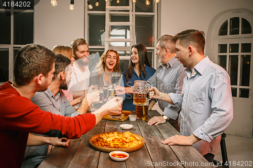 Image of Group of friends enjoying evening drinks with beer