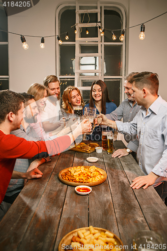 Image of Group of friends enjoying evening drinks with beer